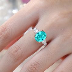 a woman's hand wearing a ring with an oval blue topazte and diamond accents