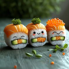 three sushi rolls with faces drawn on them sitting on top of a wooden table