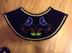 a black bib with blue butterflies and red berries on it next to a computer mouse