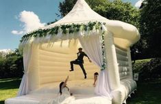 an inflatable wedding tent with two people jumping on the bed and one woman laying down