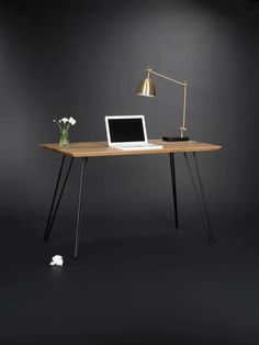 a laptop computer sitting on top of a wooden desk next to a lamp and flowers