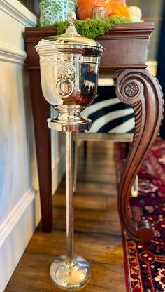 a silver goblet sitting on top of a wooden table next to a rug