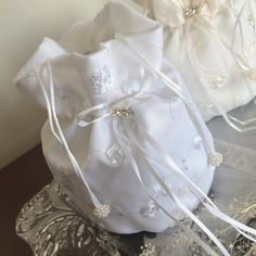 two white satin bags with ribbons tied around them on a silver tray next to each other