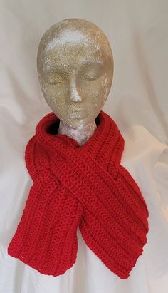 a mannequin head wearing a red knitted scarf on top of a white sheet