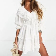 This Mini Dress From Topshop Is Made In An Ivory White Cotton, And Features Three-Quarter Length Sleeves, Layered Elasticized Eyelet Cuffs, A V-Neck With Layered Eyelet Ruffles, A Tie Waist, Frill Trim On The Skirt, And Tonal Stitching. Condition: Excellent; No Visible Signs Of Wear. Neck Label Has Been Removed. Size: 8 Approximate Measurements: Shoulder: 18.5" (47 Cm) Chest: 20" (51 Cm) Length From Back: 34" (86 Cm) Sleeve Length: 18" (46 Cm) Composition: Main: 100% Cotton. Lining: 100% Cotton. Embroidery Thread: 100% Polyester. White V-neck Ruffle Dress, Feminine White V-neck Ruffle Dress, White V-neck Ruffle Dress For Day Out, White Broderie Anglaise Mini Dress For Brunch, White Feminine V-neck Ruffle Dress, White V-neck Feminine Ruffle Dress, White Feminine Ruffle Dress For Daywear, White Broderie Anglaise Mini Dress For Day Out, White Feminine Ruffle Dress