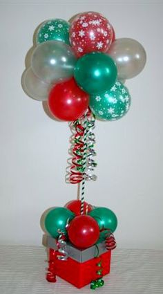 a bunch of balloons that are on top of a box and tied to a pole