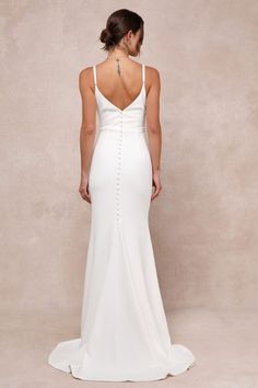 a woman in a white dress is looking down at the back of her wedding gown