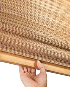 a hand is holding the edge of a bamboo mat