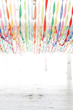 colorful streamers hanging from the ceiling in an empty room with white walls and wooden floors