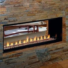 a fire place in the middle of a living room with stone walls and flooring