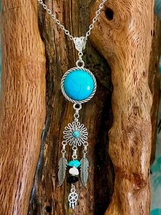 This is unique and one of a kind.Turquoise colored stone wrapped in rope like edging below sits a smaller turquoise colored stone with filigree. 2 tibetan silver feathers dangling on either side of middle dangle With small stones and tiny silver dreamcatcher The bail for holding the chain is antique Tibetan silver and generous in size if larger chain should be desired. Bohemian Sterling Silver Dangle Necklaces, Blue Bohemian Wire Wrapped Jewelry, Bohemian Blue Wire Wrapped Jewelry, Hippie Turquoise Festival Jewelry, Turquoise Feather Jewelry As A Gift, Turquoise Feather Jewelry As Gift, Bohemian Beaded Turquoise Dangle Necklace, Handmade Hippie Blue Jewelry, Nickel-free Bohemian Dangle Turquoise Necklace