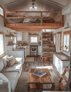 the interior of a tiny home with wood flooring and white walls, wooden stairs leading up to an upper level loft