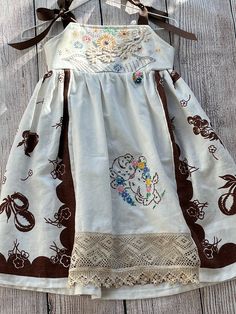 a white dress with brown trim and flowers on it