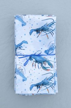 a blue and white napkin with lobsters printed on it, sitting on top of a gray surface