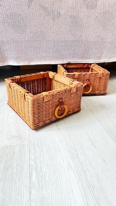 two wicker baskets sitting on the floor under a bed