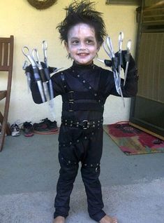 a young child dressed in black and holding up pairs of scissors to the camera with their hands