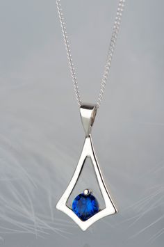 Are you searching for a dainty blue stone necklace? This sapphire pendant necklace is small but still easily noticeable. It's shape is simple but unusual and makes a delicate geometric frame around deep blue shimmering aquamarine. Since it's a minimalist and rather tiny necklace it fits women who like subtle and elegant jewelry. It will be a great everyday accessory and a piece of jewelry for special occasions as well. This sapphire necklace will be a good choice as a gift for a woman close to y Sapphire Pendant Birthstone Necklace In Sterling Silver, Sapphire Sterling Silver Pendant Birthstone Necklace, Modern Blue Diamond Cut Jewelry, Silver Teardrop Sterling Silver Birthstone Necklace, Silver Teardrop Pendant Birthstone Necklace, Sapphire Teardrop Pendant Necklace In Sterling Silver, Silver Sapphire Necklace With Polished Finish, Sapphire Sterling Silver Necklace With Diamond Cut, Blue Diamond Cut Necklace In Sterling Silver