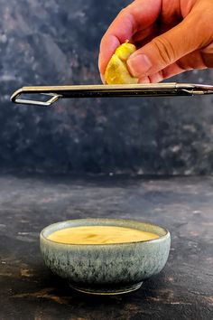 a person holding a lemon in front of a bowl with chopsticks on it