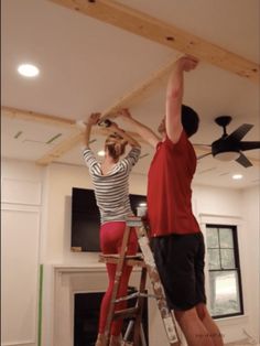 two people working on a ceiling in a house