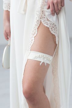 Liumy bridal garter "Champagne Embroidery Flowers" was designed with great attention to details: made from Champagne color fabric and decorated with silk ribbon embroidery, pearl beads and a small ribbon. the base made from elastic fabric so it will feel tight and comfortable on your leg made specially for you! Please leave your leg messurments in the text box bellow packed in beautifull box made from nude colour paper and decorated with gold foil letering and ribbon. So it can be a great presen Elegant White Bridal Accessories For Wedding Night, Fitted White Bridal Belt, Elegant Fitted Bridal Accessories For Wedding Night, White Fitted Bridal Belt For Ceremony, Fitted Lace Bridal Belt For Ceremony, Satin Bridal Belt With Ribbon For Wedding, Elegant White Bridal Belt With Satin Bow, Fitted Satin Bridal Belt With Ribbon, Lace Bridal Belt For Ceremony