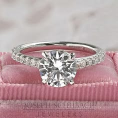 a diamond engagement ring sitting on top of a pink velvet box