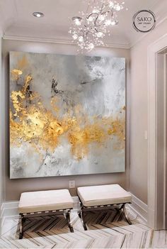 a large painting hanging on the wall above two benches in front of a chandelier