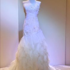 a white wedding dress is displayed on a mannequin in front of a wall