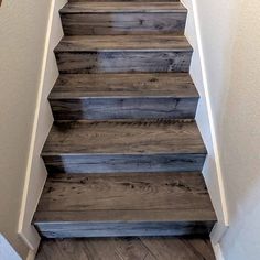 a wooden stair case with white walls and wood flooring on the bottom half of it