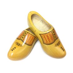 two wooden shoes are sitting next to each other on a white surface and one is painted yellow