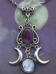 A stunning piece of Jewellery for any occasion . A filigree bail holds this beautiful triple moon Amethyst pendant . Consisting of a 1.5x1cm Oval Amethyst set in an ornate cabochon tray , suspended from the main pendant are two silver tone double sided crescent moons . The centre hanging pendant is a glass cabochon and tray featuring a stunning full moon. The total size of the pendant from Bail to moon cabochon is 6cm . The chain is 20inches .  I include a card ( the necklace will be presented on the card in clear film envelope. I include a purple organza bag . Mystical Purple Jewelry With Moon Charm, Bohemian Amethyst Moon Charm Jewelry, Purple Bohemian Jewelry With Moon Charm, Bohemian Purple Jewelry With Moon Charm, Purple Moon Charm Pendant Necklace, Purple Pendant Necklace With Moon Charm, Mystical Amethyst Moon Phase Jewelry, Purple Spiritual Jewelry With Moon Charm, Bohemian Amethyst Moon Phase Jewelry