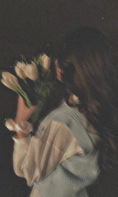 a woman is holding flowers in her hand