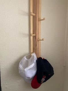 three hats are hanging on the wall and one is holding a rack with two baseball caps