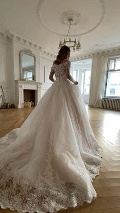 a woman in a wedding dress is standing on the floor with her back to the camera