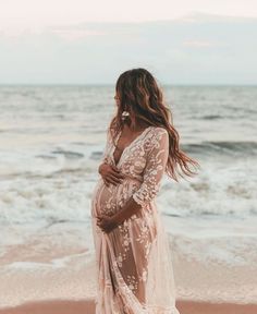 a pregnant woman standing on the beach