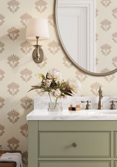 a bathroom sink with a mirror above it and flowers in the vase on the counter