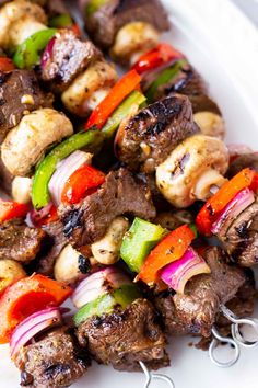 meat and vegetable kabobs on a white plate