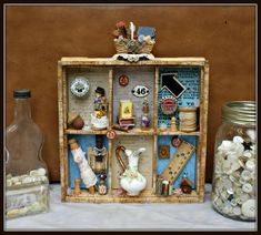 there is a small shelf with many items in it and some jars on the table