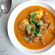 a bowl of soup with meat and cilantro garnished with cilantro