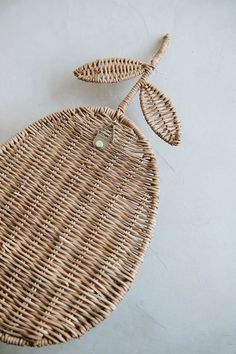 a wicker bag with two leaves hanging from it's side on a white surface