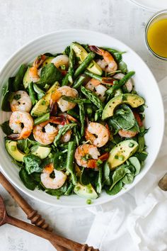 a white bowl filled with shrimp and veggies next to a glass of orange juice