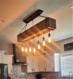 a wooden beam hanging from the ceiling in a kitchen with light bulbs coming out of it