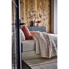 a bed sitting next to a wooden wall in a room with lots of pillows on top of it