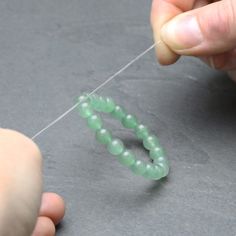 a person is holding a string with beads on it and threading the bead together