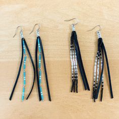 three pairs of beaded and leather earrings on a wooden surface with beads hanging from them