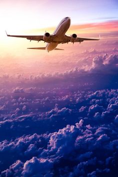 an airplane flying above the clouds at sunset