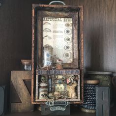 there is a wooden box with various items in it on top of a shelf next to other objects