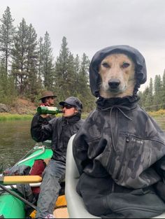 two men and a dog are in a canoe on the water, one is wearing a raincoat