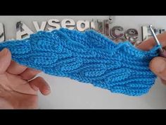 two hands are working on a blue knitted object