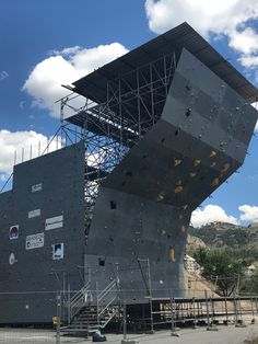 an outdoor climbing wall with scaffolding on the side and stairs leading up to it