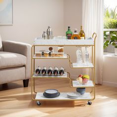 a bar cart with drinks and plates on it in a living room next to a couch